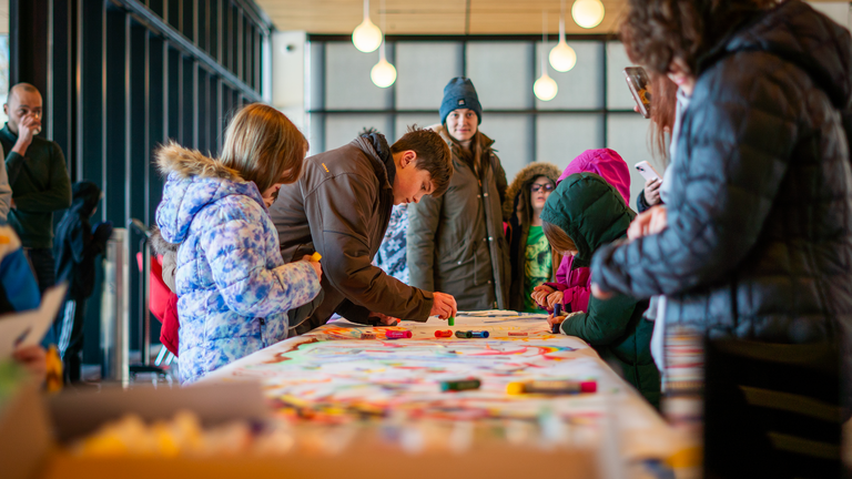 A group of people crowd around the mural. 