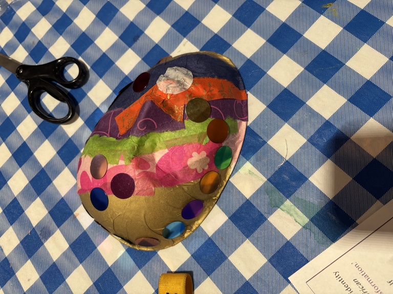 One student's mask, featuring diagonal stripes made of different color tissue papers.