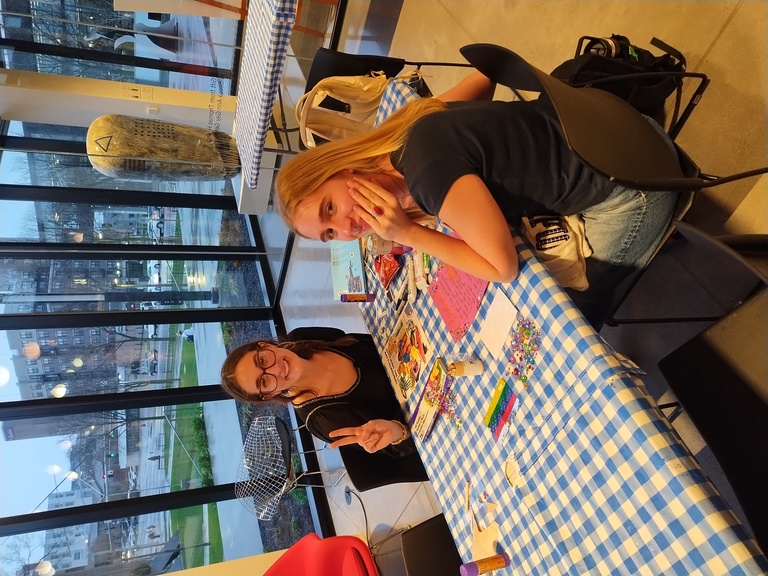 Two students sit at a table with a blue and white checkered table cloth and smile at the camera.