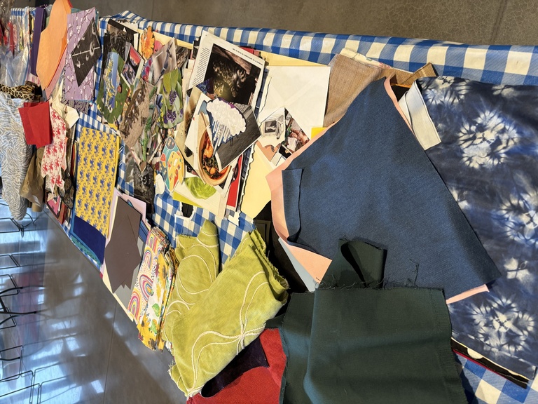 Collage elements--paper, fabric, and more--spread out on a table.