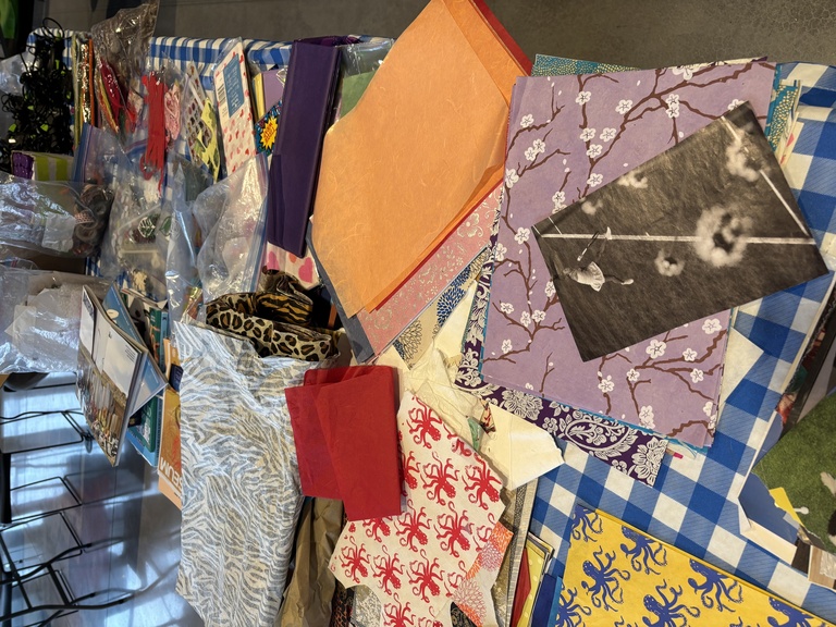 Collage elements--paper, fabric, and more--spread out on a table.