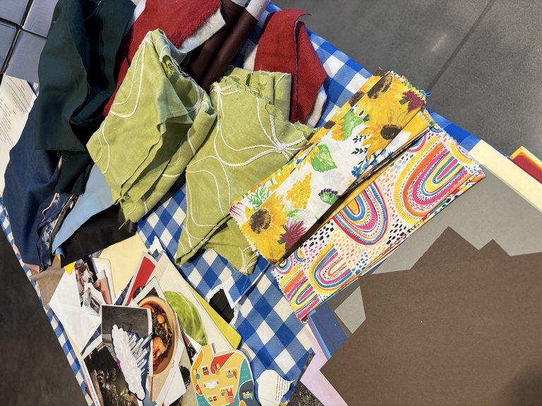 Collage elements--paper, fabric, and more--spread out on a table.