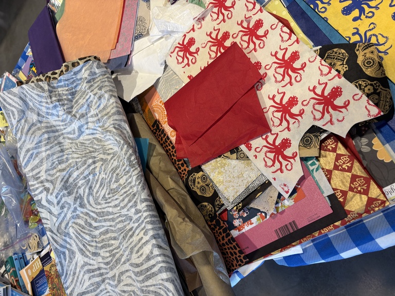 Collage elements--paper, fabric, and more--spread out on a table.