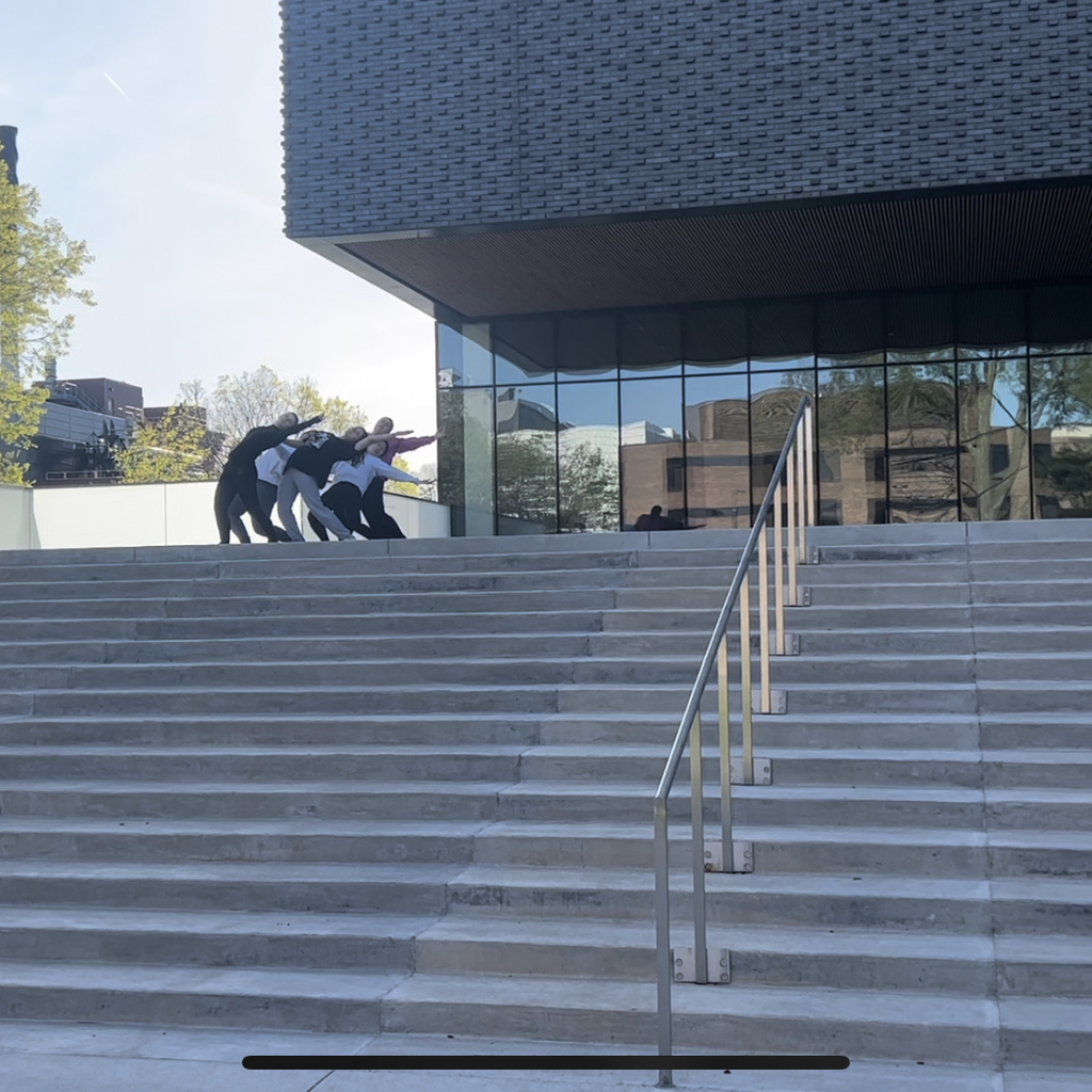 A still image from a video of a dance project choreographed by Katherine Shamdin. In it, 5 students dance on the front steps of the Stanley.