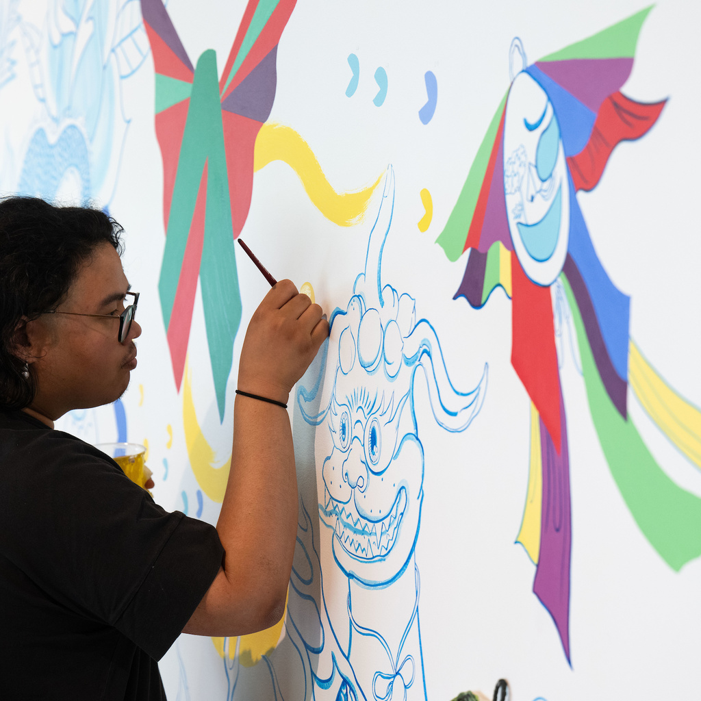 A photo of Stanley student employee, Shaun Mallonga, working on Jiha Moon's mural, 'One An Other,' in the Stanley Museum of Art lobby.