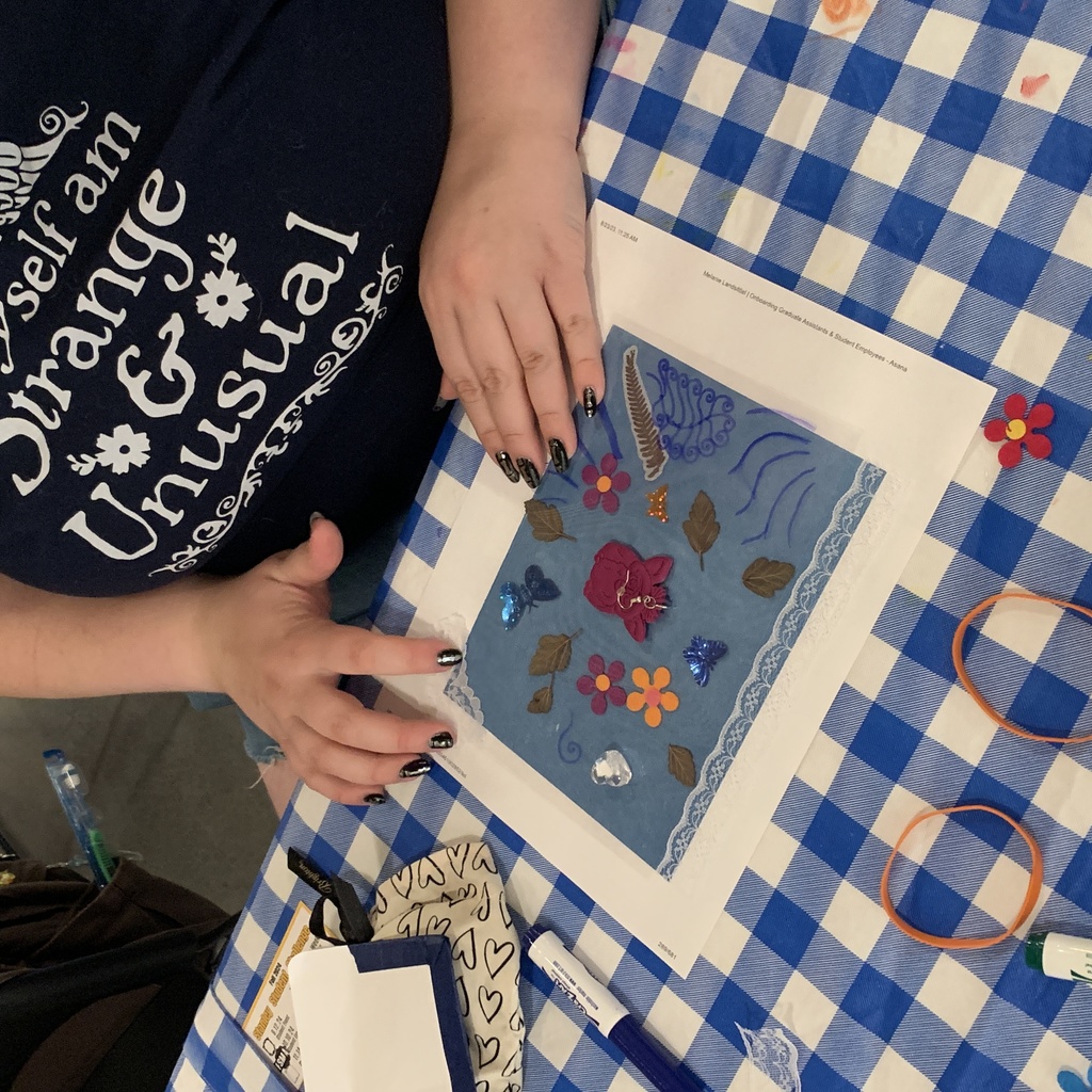 A close up of a student working on assembling their cyanotype; they are laying various materials on top of the blue paper.