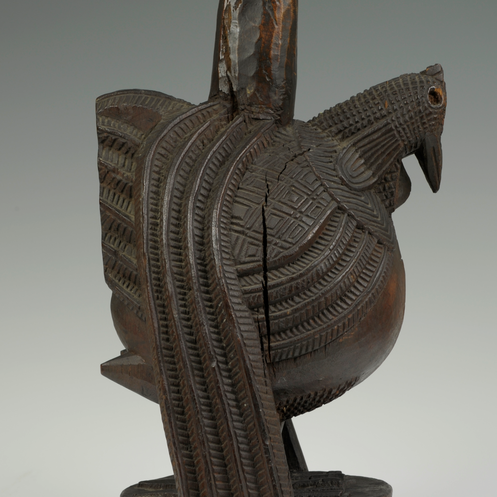 A wooden object with carvings in the shape of a hen