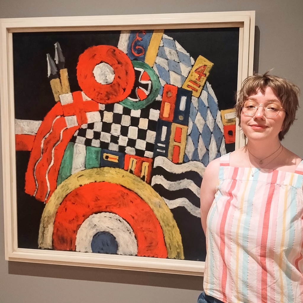 Lauren Smith poses in front of Marsden Hartley's painting, "E," in the Stanley Museum of Art's galleries.