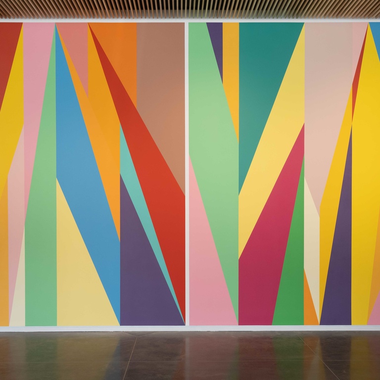 A wall painted with brightly colored geometric shapes. Each shape has a unique color.