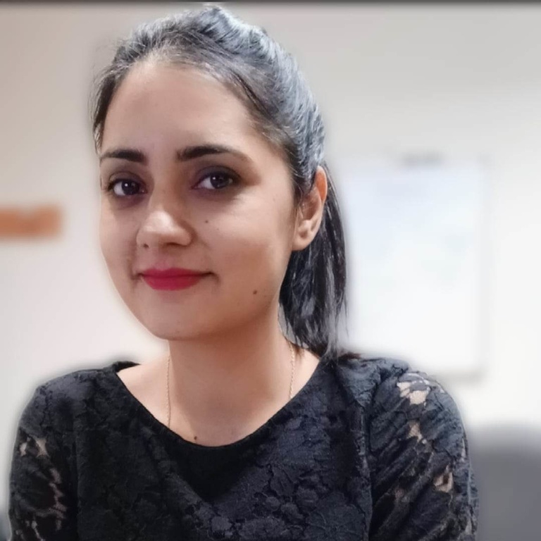 A photo of Gul Rukh Mehboob: she is wearing a black lace dress and smiling downward at the camera.