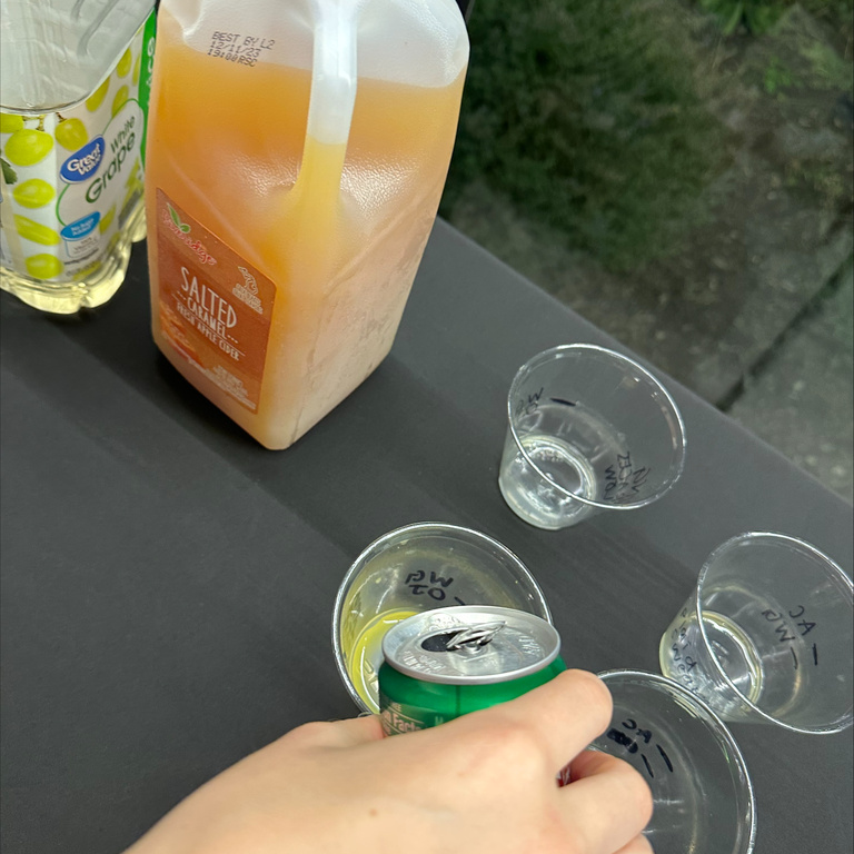 close up image of a hand pouring a canned ginger ale into a clear plastic cup 