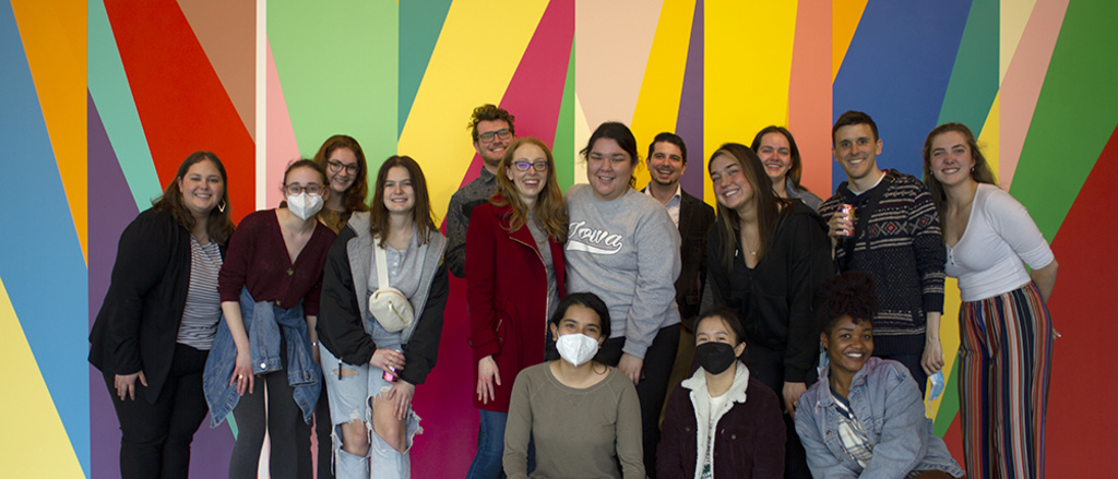 A group of students stands in front of a brightly painted wall