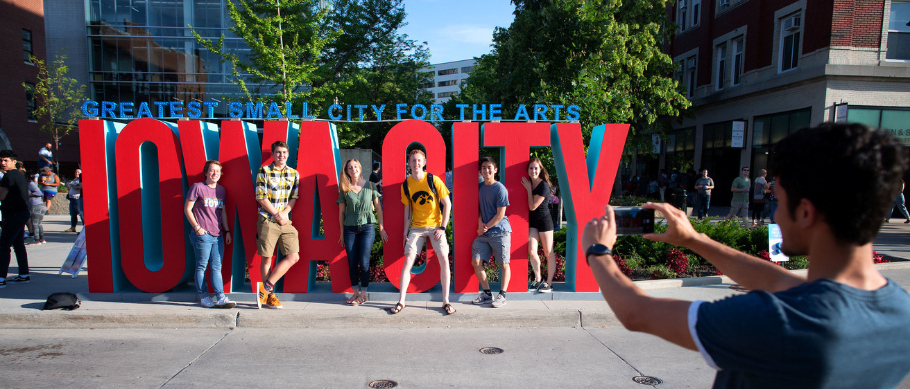 Large red letters spelling "Iowa City" with people posing in front for a photograph