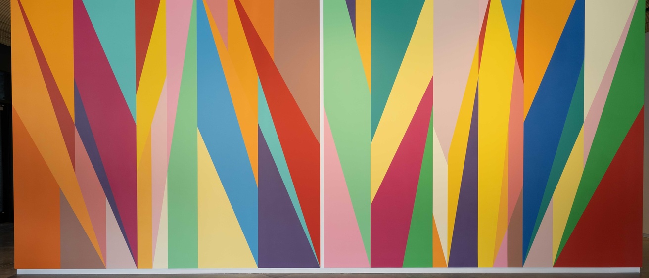 A wall painted with brightly colored geometric shapes. Each shape has a unique color.