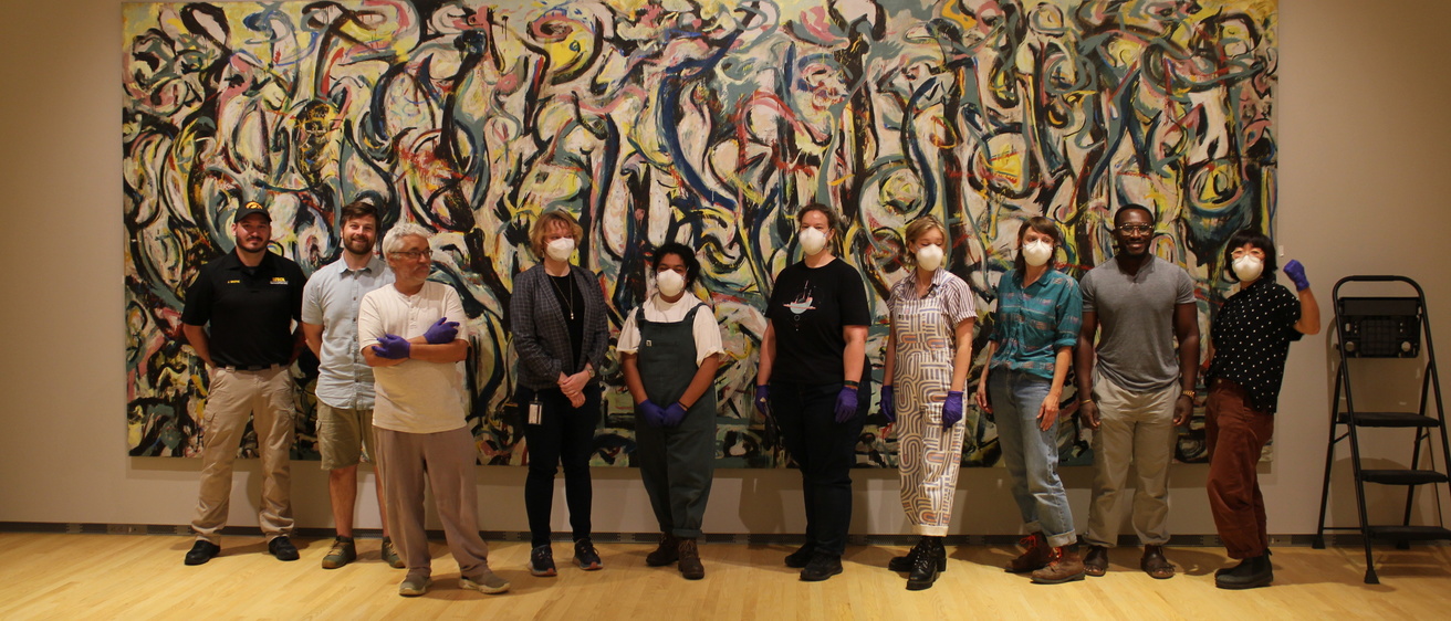 Museum staff pose in front of Jackson Pollock's "Mural" following installation.