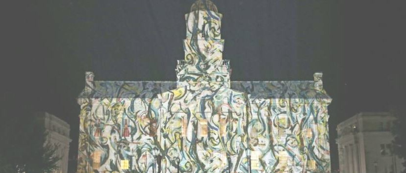 The Old Capitol building at the University of Iowa with a projected image of an abstract painting across the face of the building