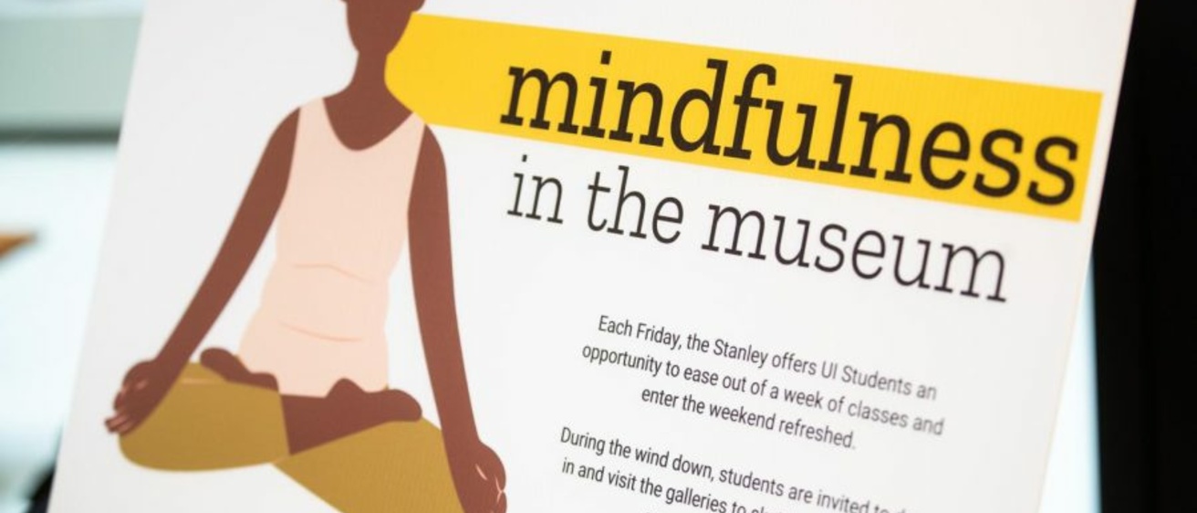 Signage with an illustrated figure of a woman sitting cross-legged on the floor meditating.