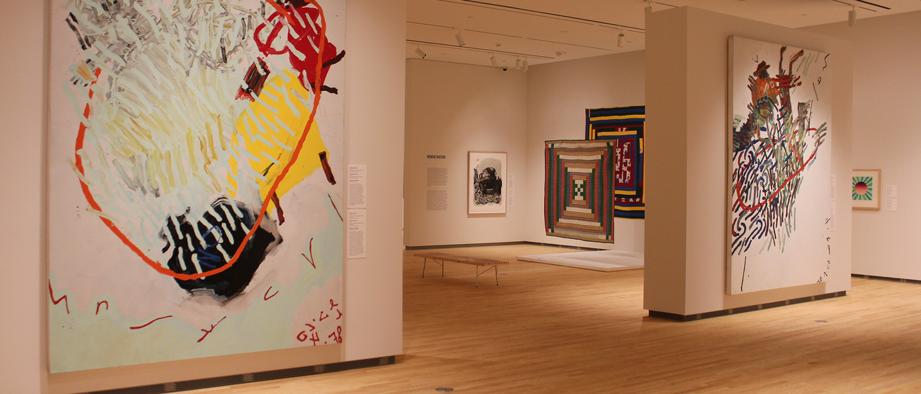 An installation shot of the galleries at the Stanley Museum of Art. In the foreground, two large works by Oliver Lee Jackson can be seen; behind them, a glimpse at Gee's Bend quilts.