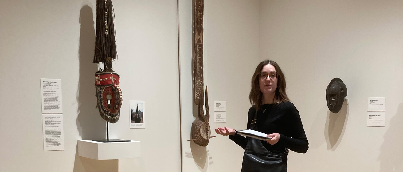 A photo of Amelia Goldsby standing and presenting in one of the African art galleries at the Stanley Museum of Art.