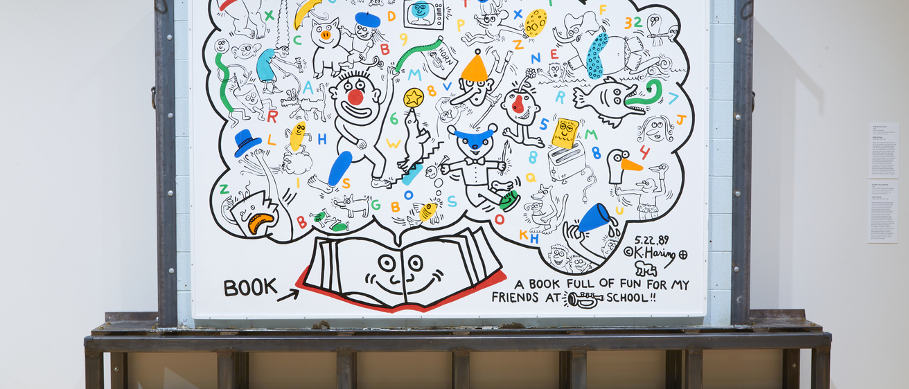 A large white mural filled with colorful drawings, mounted on a concrete wall held together by a metal base