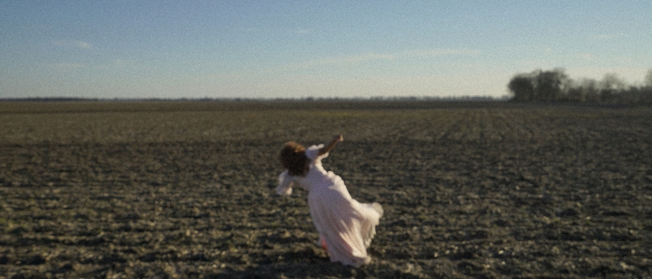 A woman in a white dress in the middle of an open field