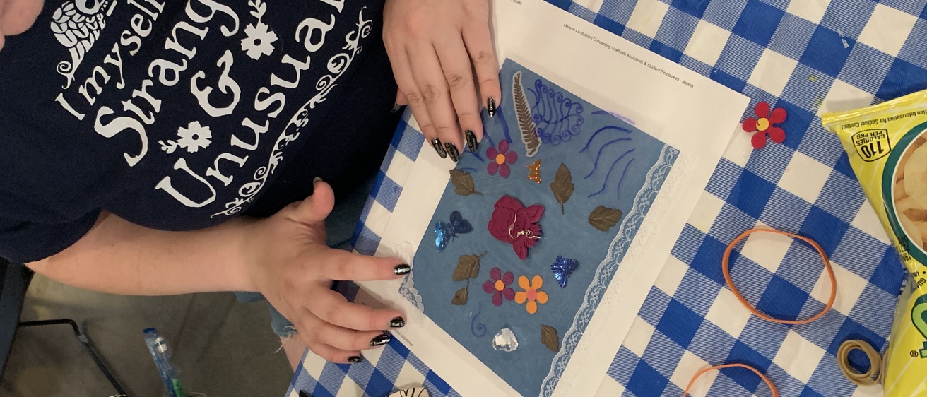 A close up of a student working on assembling their cyanotype; they are laying various materials on top of the blue paper.
