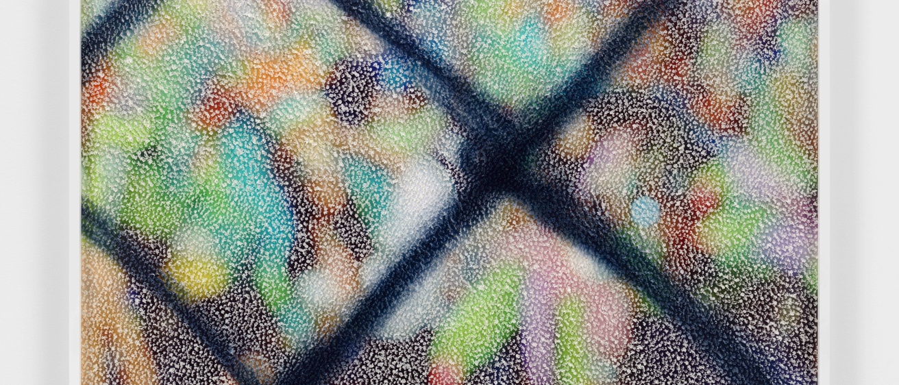 A framed abstract image on a wall. Blurred colors of blue, green, orange, and black are beneath a mottled white pattern with a textured overlay. 