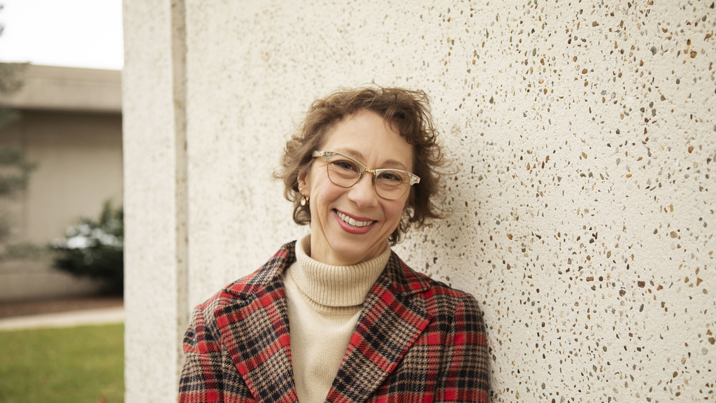 woman with short hair, glasses, and a plaid jacket