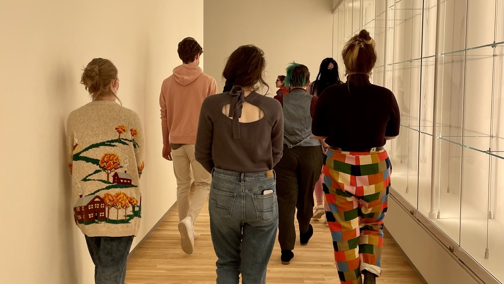 A group of students, seen from the back, walk through a Stanley Museum of Art gallery