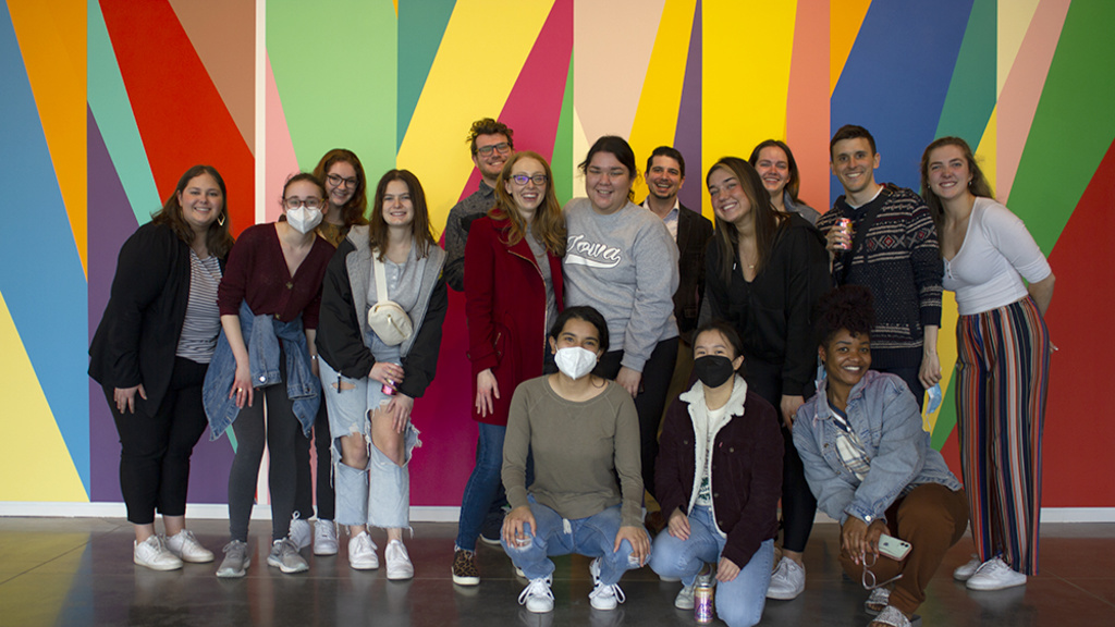 A group of students stands in front of a brightly painted wall
