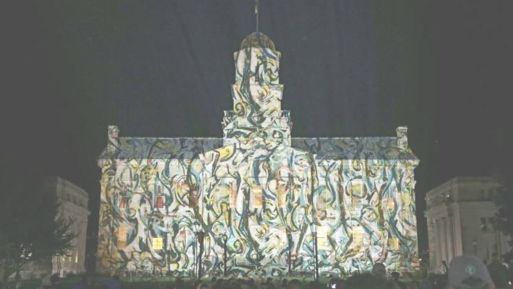 The Old Capitol building at the University of Iowa with a projected image of an abstract painting across the face of the building