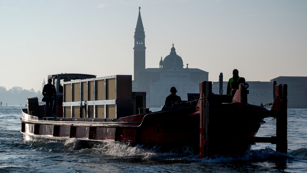 A large wooden crate is transported on a barge in the Grand Canal, Venice, Italy