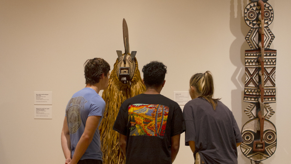 three students look at an African mask