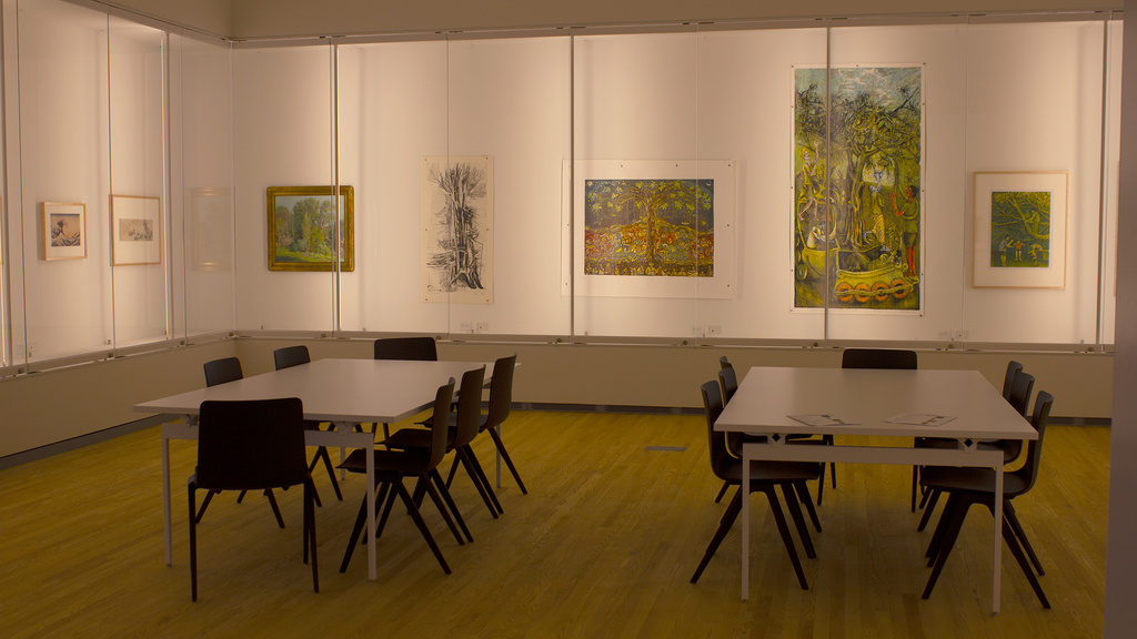 A room with glass-front cases filled with artworks and lit from within
