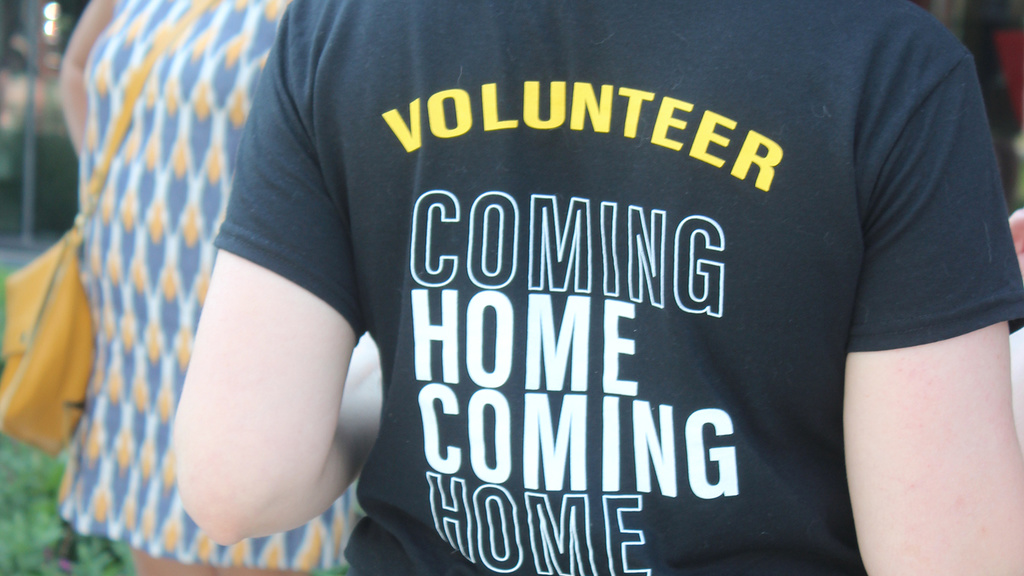 Woman seen from behind wearing a black t-shirt that reads "Volunteer"