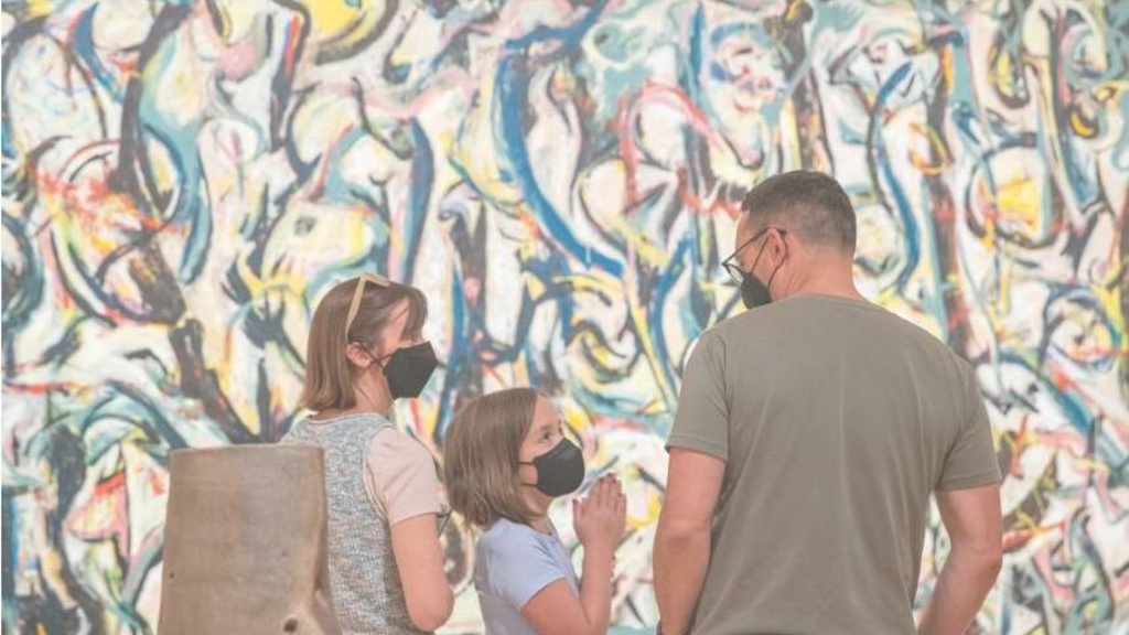 Beatrice Casto, 9, of Iowa City, talks with her parents, Heidi Casto (left) and Andrew Casto while looking at Jackson Pollock’s masterpiece, “Mural,” during the opening weekend event at the Stanley Museum of Art on August 26, 2022. The Castos are art instructors at the University of Iowa art school and wanted to take their daughter to the opening of the museum. Photo by Savannah Blake, The Gazett