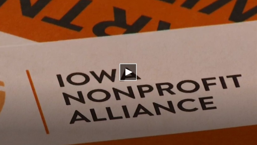 A screenshot of a video still with a red and black background with text overlaid that reads "Iowa Nonprofit Alliance."