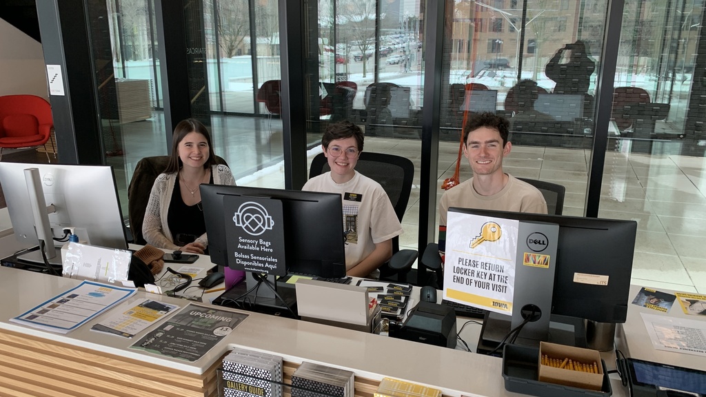 A photo of three gallery hosts seated at the Stanley Museum of Art front desk.
