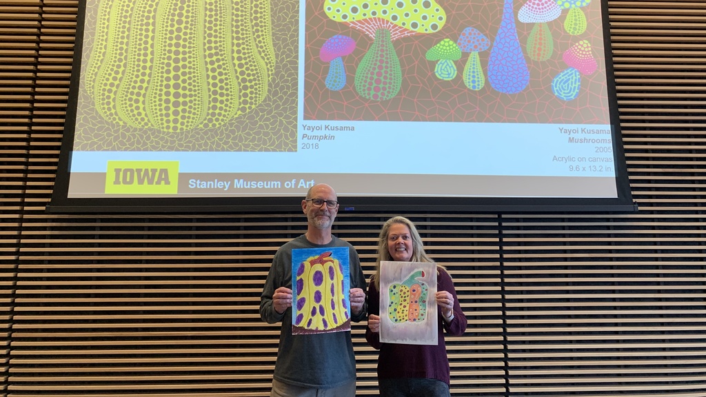 two adults standing in front of examples of Kusama's 