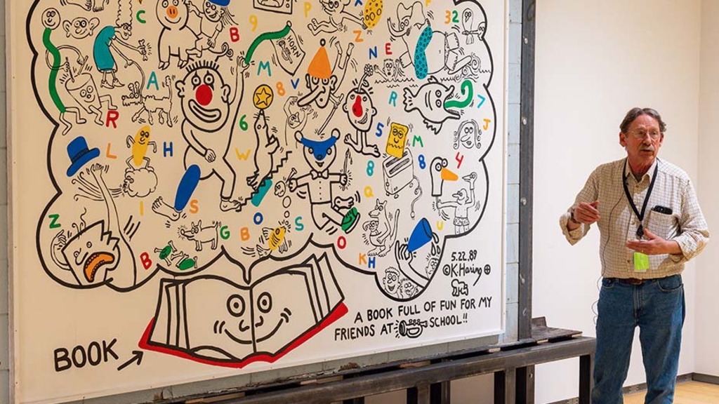 Ron Harvey, an art conservator with Tuckerbrook Conservation, assists with the installation of Keith Haring's A Book Full of Fun earlier this spring at the University of Iowa Stanley Museum of Art.