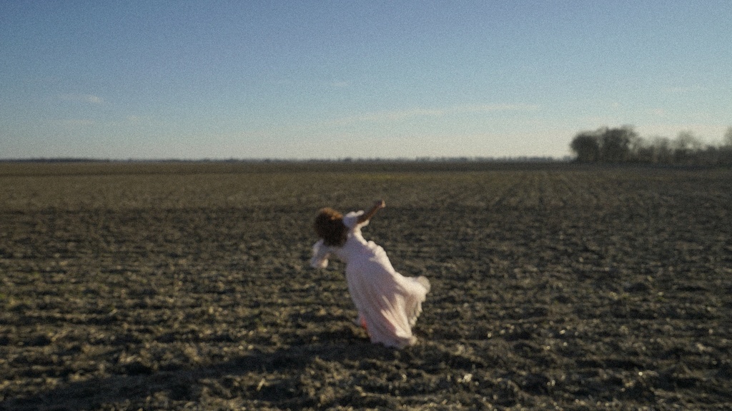 A woman in a white dress in the middle of an open field