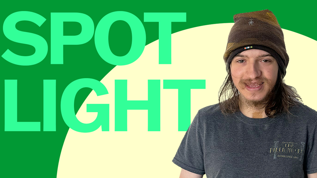 A photo of Luke Krchak superimposed onto a green background, with the words "Student Spotlight." Luke is wearing a brown beanie and a blue t shirt and is smiling.