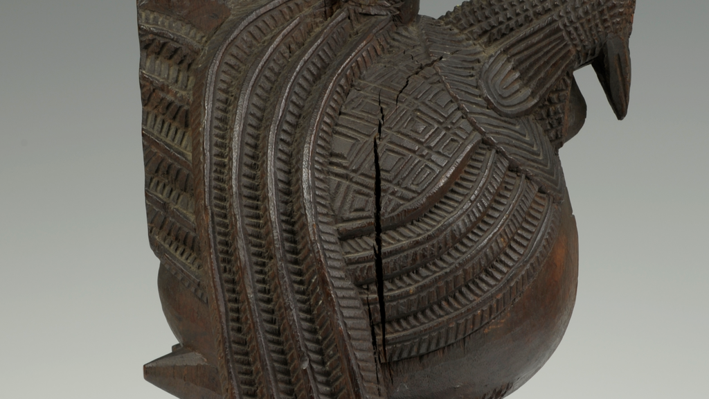 A wooden object with carvings in the shape of a hen