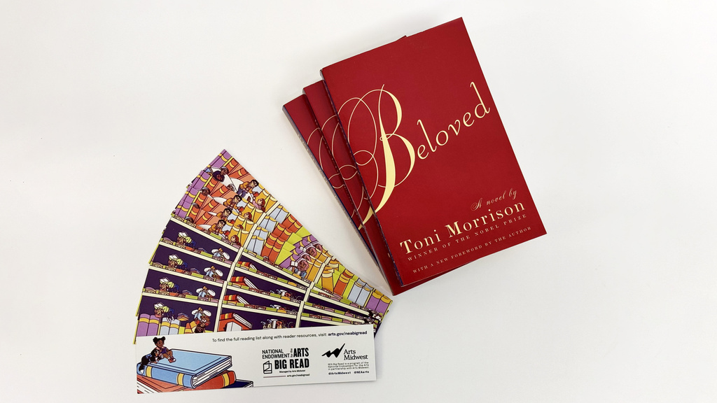 Multiple bookmarks and copies of a red book fanned out with the text "Beloved. A novel by Toni Morrison."