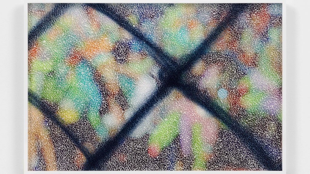 A framed abstract image on a wall. Blurred colors of blue, green, orange, and black are beneath a mottled white pattern with a textured overlay. 