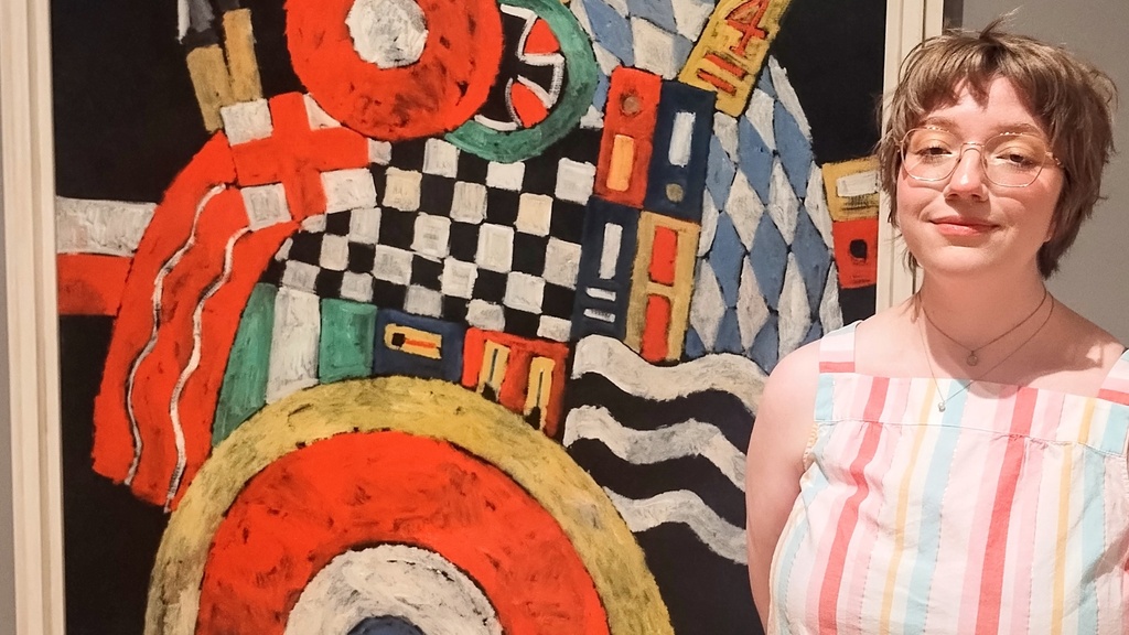 Lauren Smith poses in front of Marsden Hartley's painting, "E," in the Stanley Museum of Art's galleries.