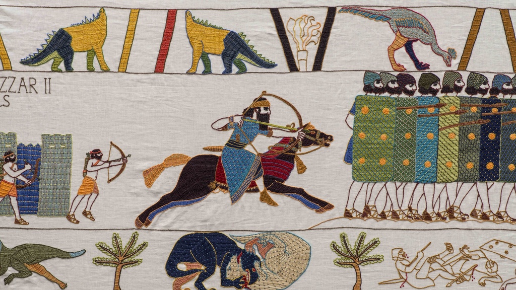 Embroidered tapestry depicting warriors in battle, archers, soldiers with shields, horses, palm trees, and dinosaurs in the style of the Bayeux Tapestry.