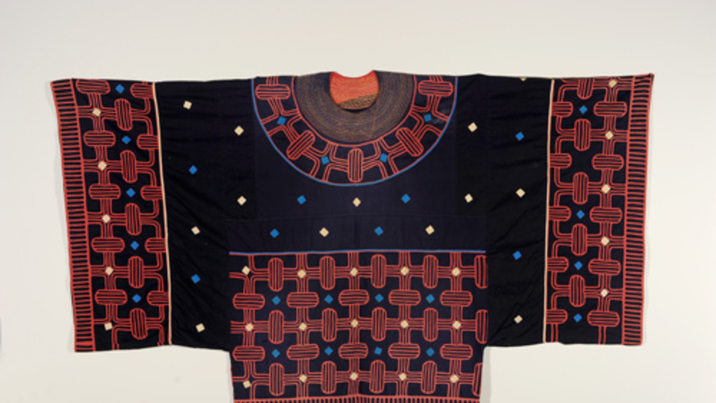 Garment with wide square sleeves. It has a navy base with detailed red patterns on the sleeves, around the neck, and on front bottom. Small yellow and blue diamonds are scattered throughout.