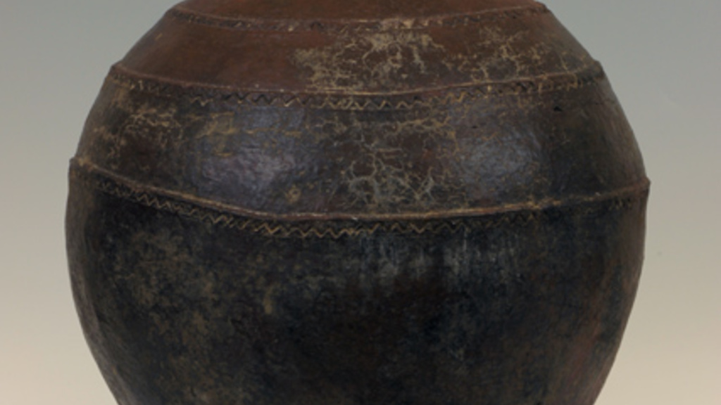 Dark brown, rounded vessel with a short round base and small circular opening at the top.
