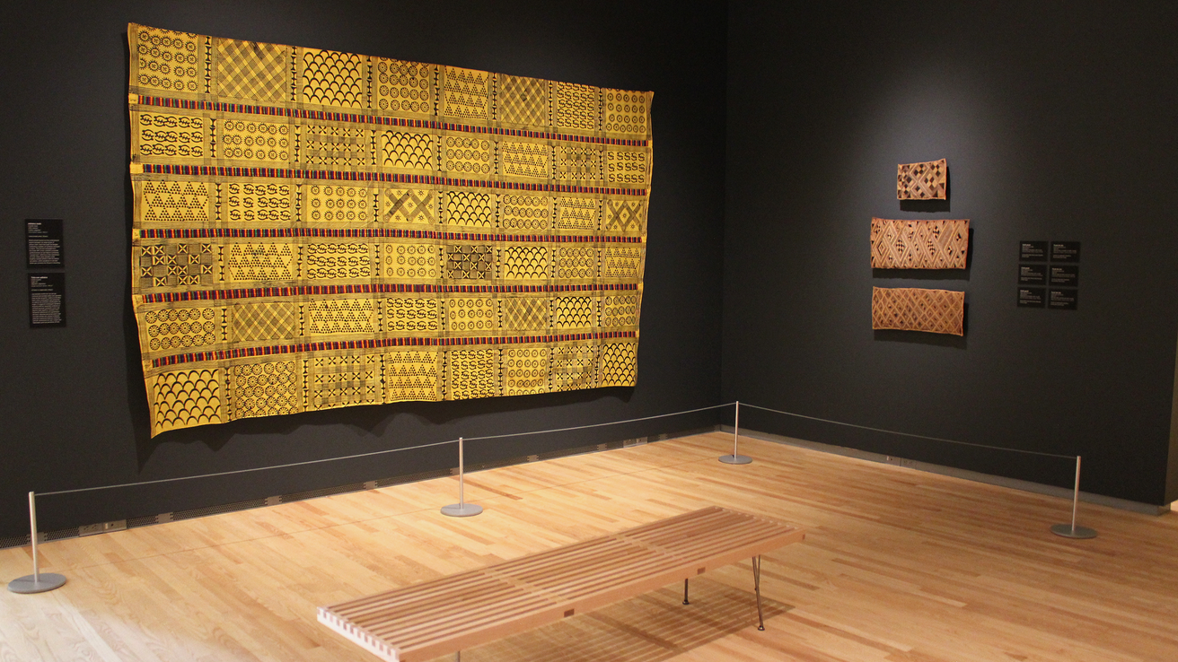 An installation shot of "Centering on Cloth," featuring a large yellow adinkra cloth.